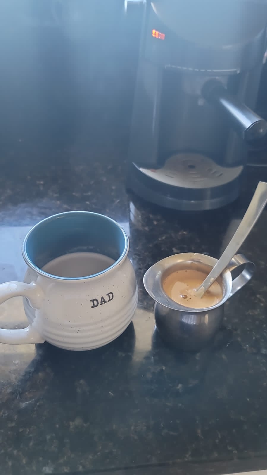 Close-up of a Cuban cafecito being poured from a moka pot into a demitasse cup, revealing a thick, frothy espuma on top.